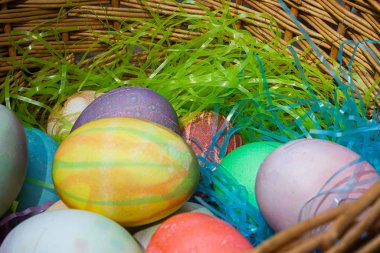 Renkli yumurtalar ve plastik otlarla örülmüş bir Paskalya sepeti.