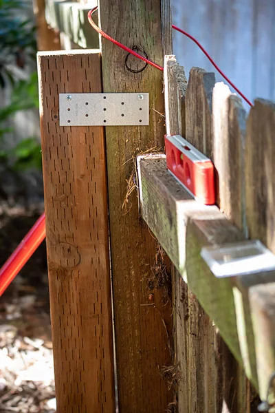 Stare ogrodzenie z narzędziami i metalowym wspornikiem na ogrodzeniu — Zdjęcie stockowe