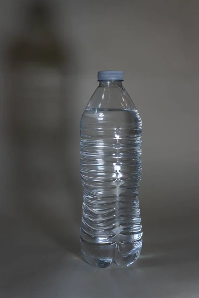 Πλαστικό μπουκάλι νερό με φως και σκιές κατά του λευκού — Φωτογραφία Αρχείου