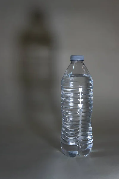 Plastic water bottle with light and shadows against white — Stock Photo, Image