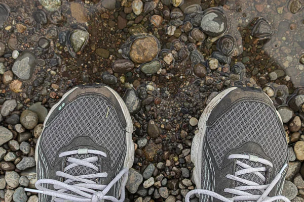 old dirty sneakers standing on stone and dirt running path