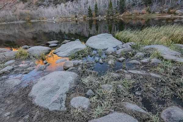 Zrcadlený odraz v klidném jezeře s pobřežní sluneční září — Stock fotografie