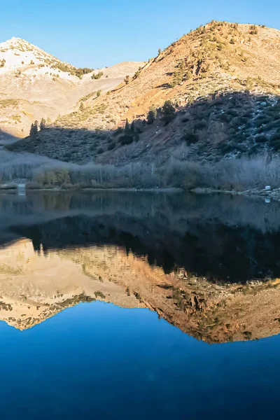 Jasně modrý ještě jezero povrch odrážející okolní hory — Stock fotografie