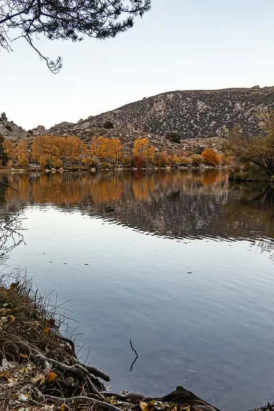 Velké jezero odrážející barvy podzimních stromů a hory — Stock fotografie