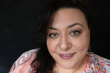 Uzun saçlı, esmer, etnik bir kadın.