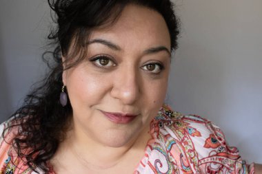 Uzun saçlı, esmer, etnik bir kadın.