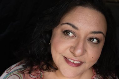 Uzun saçlı, esmer, etnik bir kadın.