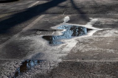 Yağmurdan sonra yansıtıcı su birikintisinin yanındaki yağmur gideri