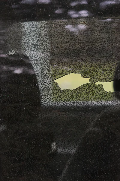 Θρυμματισμένο γυαλί ενός παραθύρου αυτοκινήτου που μετακινείται με ένα μαύρο γάντι — Φωτογραφία Αρχείου