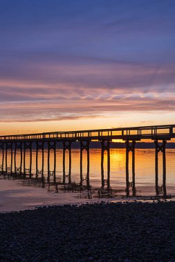 Güneş uzun bir balıkçı limanının üzerinde batıyor