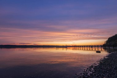 Güneş uzun bir balıkçı limanının üzerinde batıyor