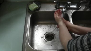 Genç kadın lavaboda ellerini yıkamak için yeşil sabun kullanıyor.