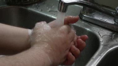 Genç erkek elleri lavaboda ellerini yıkamak için yeşil sabun kullanır.