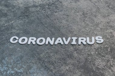 Koronavirüs gri arkaplanda beyaz harflerle yazılmış.