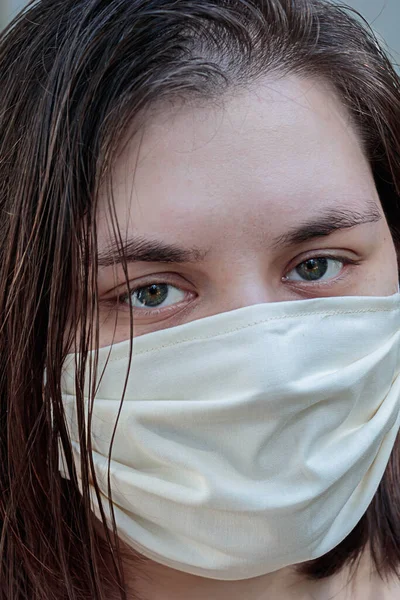 Korunmak için maske takmış koyu renk saçlı genç bir kadın.