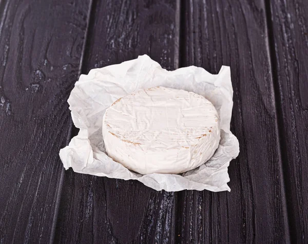 Queijo Brie Papel Branco Uma Mesa Madeira — Fotografia de Stock