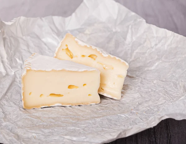 Queijo Brie Papel Branco Uma Mesa Madeira — Fotografia de Stock