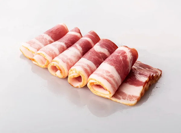Beyaz arka planda izole edilmiş taze kırmızı fesleğenle dilimlenmiş domuz pastırması ve rulo.