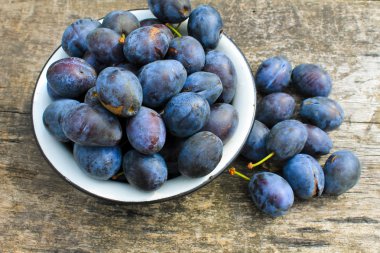 Eski ahşap arka plan üzerinde rustik kase taze Erik