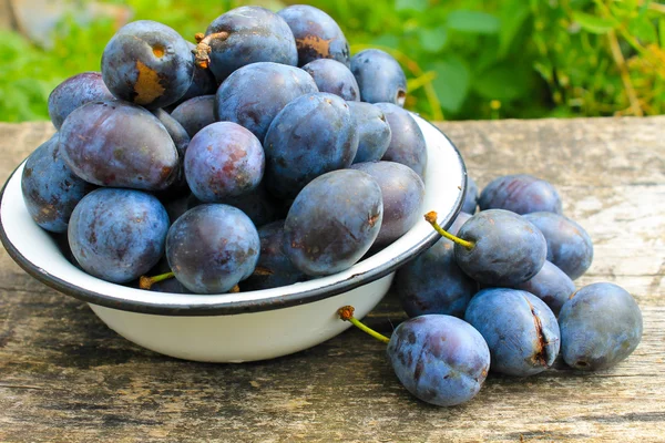 Prugne fresche in ciotola rustica su fondo legno antico — Foto Stock