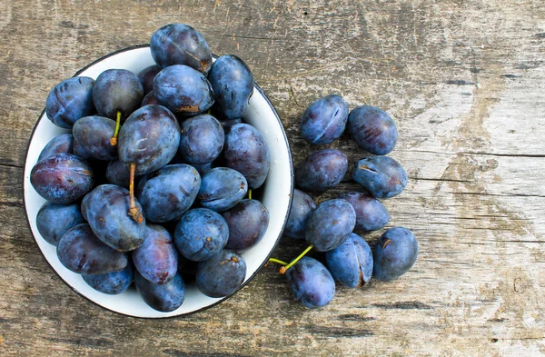 Eski ahşap arka plan üzerinde rustik kase taze Erik