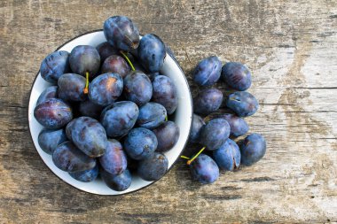 Eski ahşap arka plan üzerinde rustik kase taze Erik