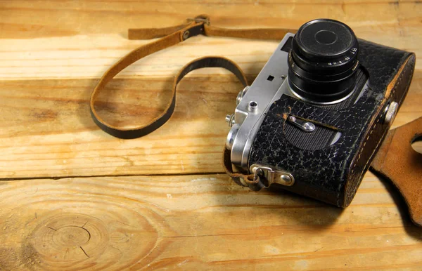 Старая ретро камера в кожаном чехле на деревянном фоне — стоковое фото