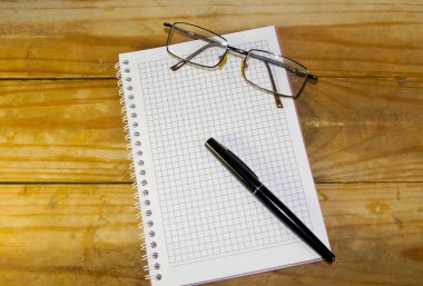 Defter ile gözlük ve dolma kalem ahşap masa