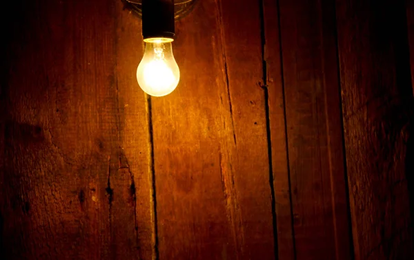 Electric light bulb on wooden background — Stock Photo, Image