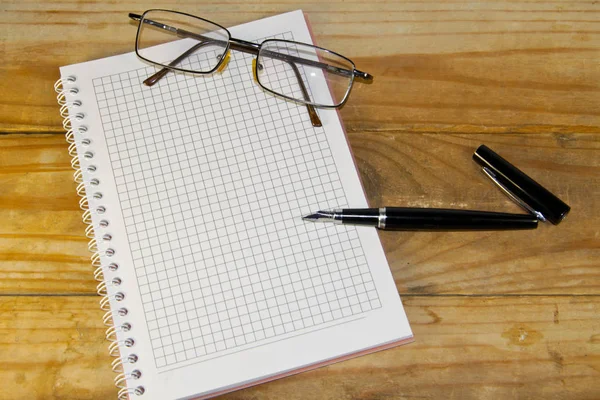 戴着眼镜，钢笔在木桌上的笔记本 — 图库照片
