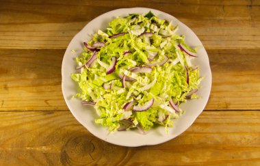 Çin lahanası ve ahşap masa üzerinde soğan salatası
