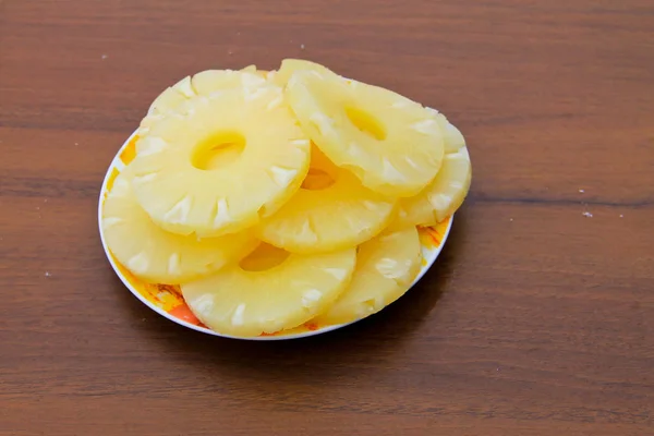 Κονσέρβες ανανά σε ένα πιάτο στο ξύλινο τραπέζι — Φωτογραφία Αρχείου