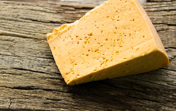 Piece of cheese on a wooden background — Stock Photo, Image