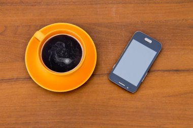 Fincan kahve ve ahşap masa üstünde smartphone
