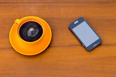 Fincan kahve ve ahşap masa üstünde smartphone