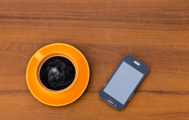 Fincan kahve ve ahşap masa üstünde smartphone