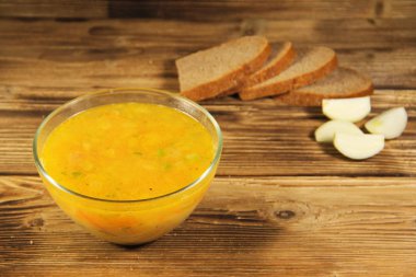 Ahşap masa üzerinde cam kapta taze bezelye çorbası