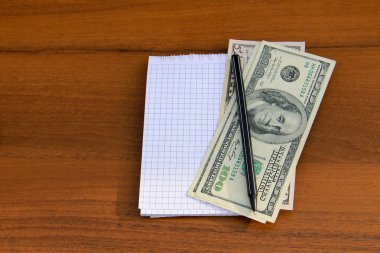 Ahşap masa üzerine kalem ve Doları nakit ile not etmek
