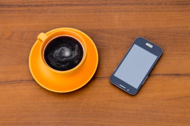 Fincan kahve ve ahşap masa üstünde smartphone