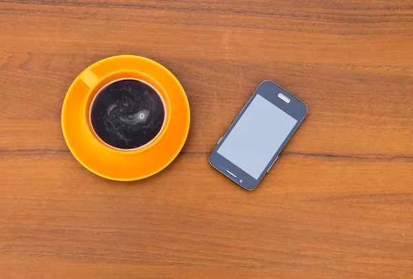Tasse Kaffee und Smartphone auf Holztisch — Stockfoto
