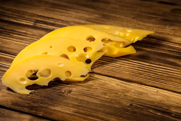 Plakjes van Zwitserse kaas op houten tafel — Stockfoto