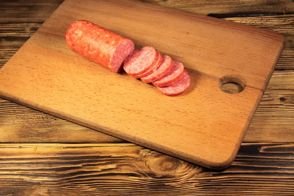 Сосиски, нарезанные на доске на деревянном столе — стоковое фото