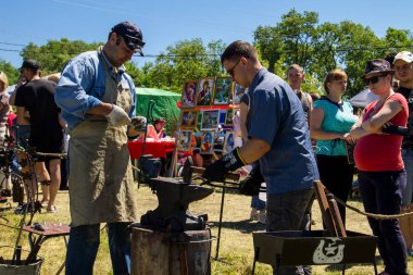 Genç bir adam sanatı deneyimli demirci öğretir