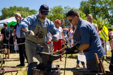Genç bir adam sanatı deneyimli demirci öğretir