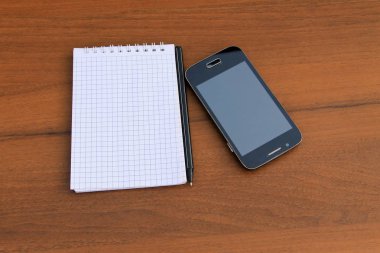 Kalem ve ahşap masa üzerinde smartphone ile not etmek
