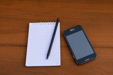 Kalem ve ahşap masa üzerinde smartphone ile not etmek