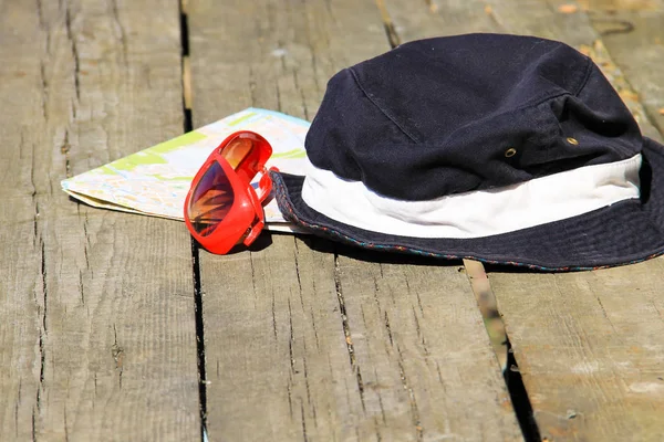 Έννοια του ταξιδιού. Καπέλο, γυαλιά ηλίου κόκκινο και χάρτη σε φόντο ξύλινη — Φωτογραφία Αρχείου