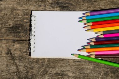 Renkli kalemler ve eski ahşap masa boş not defteri