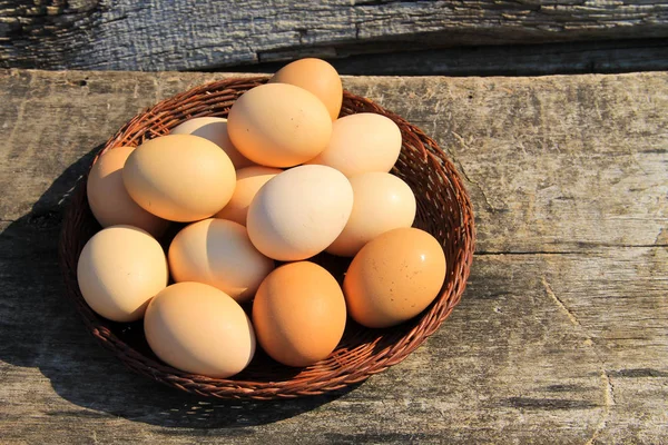 Eggs in wicker basket on wooden table — Stock Photo, Image