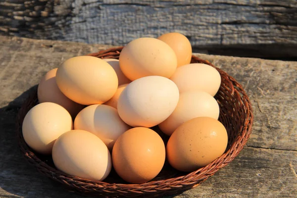 Eggs in wicker basket on wooden table — Stock Photo, Image
